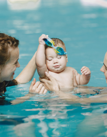 two adults and baby in pool