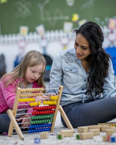 Adult and child in a classroom using slider beads.