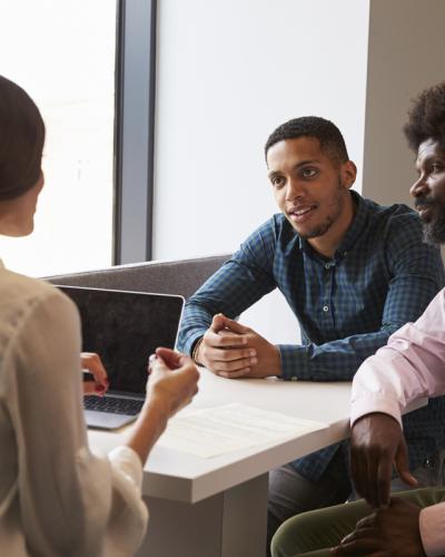 Three adults interacting at a table.