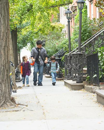 Man walking on urban street, holding hands with two children