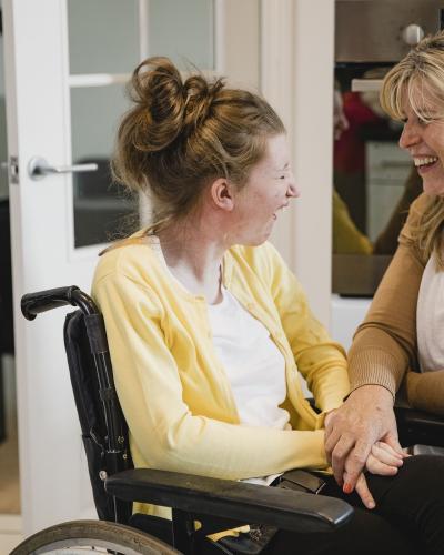 Young female in a chair laughing with adult female.